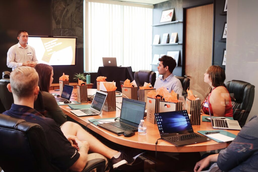 How to Choose a Digital Marketing Agency in Australia | Digital marketing agency team in a boardroom meeting with laptops open while a presenter discusses strategy in front of a screen