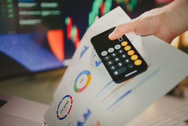 Hand using a calculator over financial charts and graphs while reviewing marketing budget figures during an economic downturn | Marketing in a Downturn Australia: What SMBs Should Do